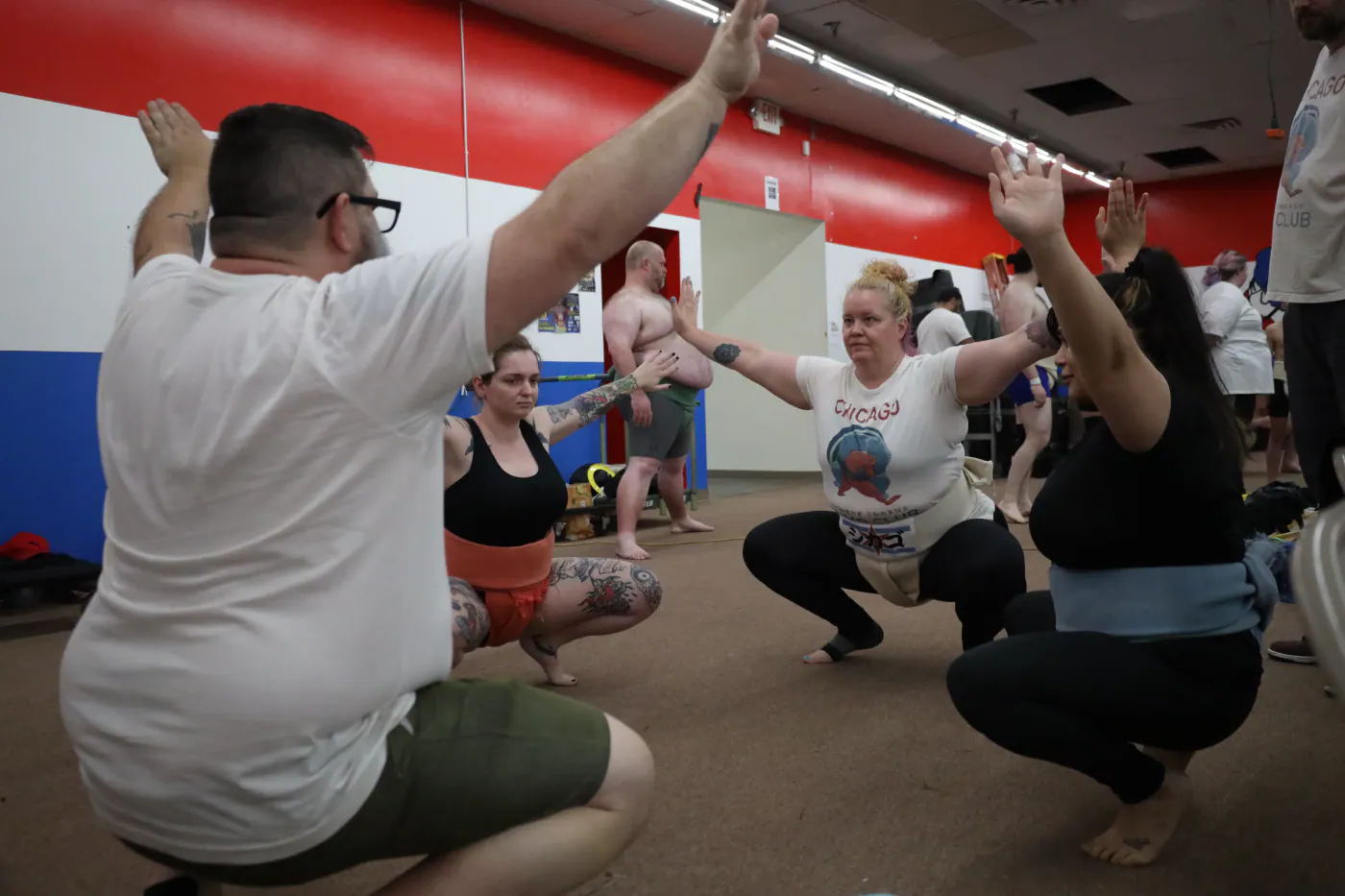 Club members in a low squat with arms raised during indoor practice