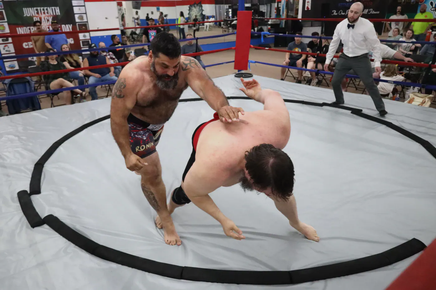 A wrestler bending an opponent toward the ring during a match