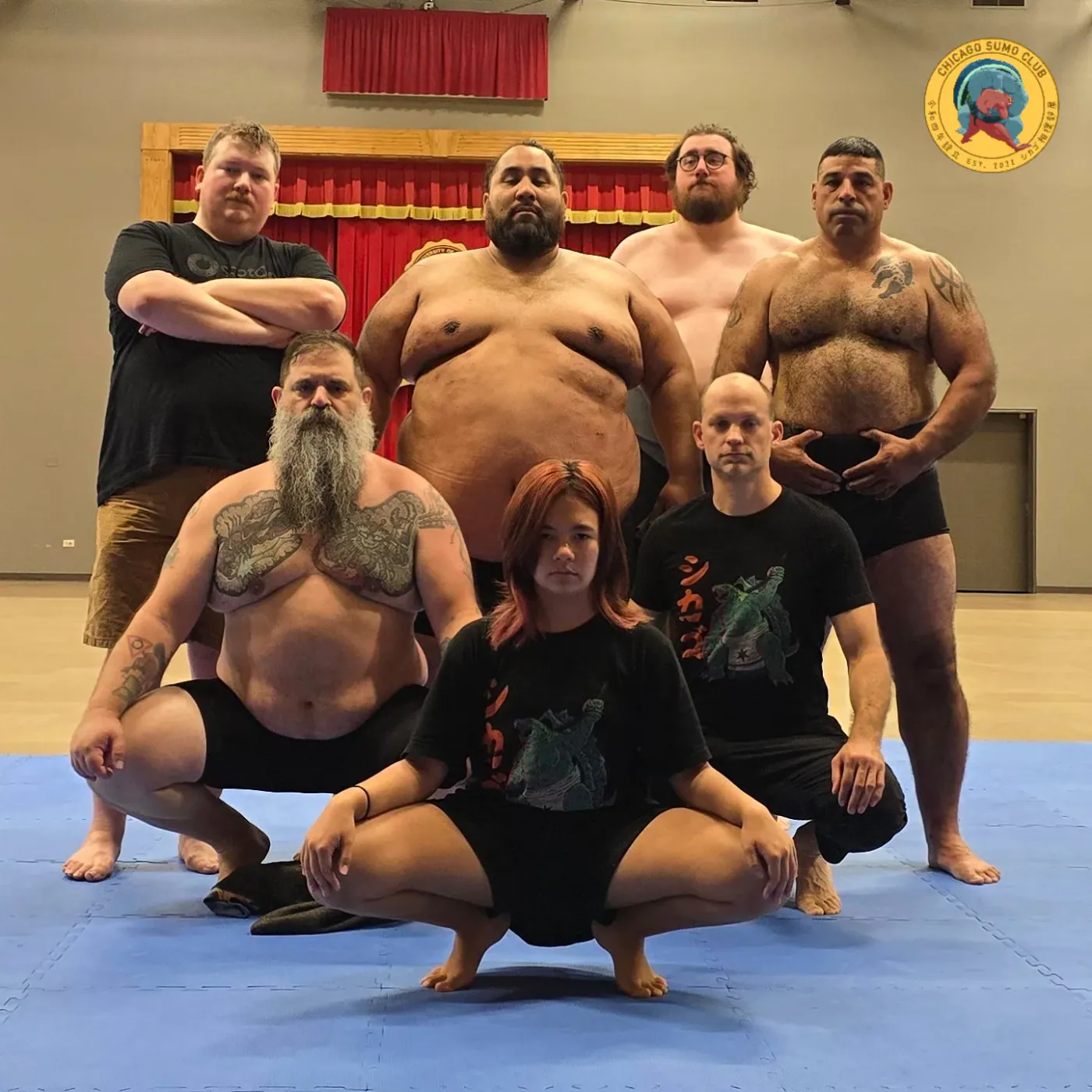 Chicago Sumo Club members posing in front of a stage curtain